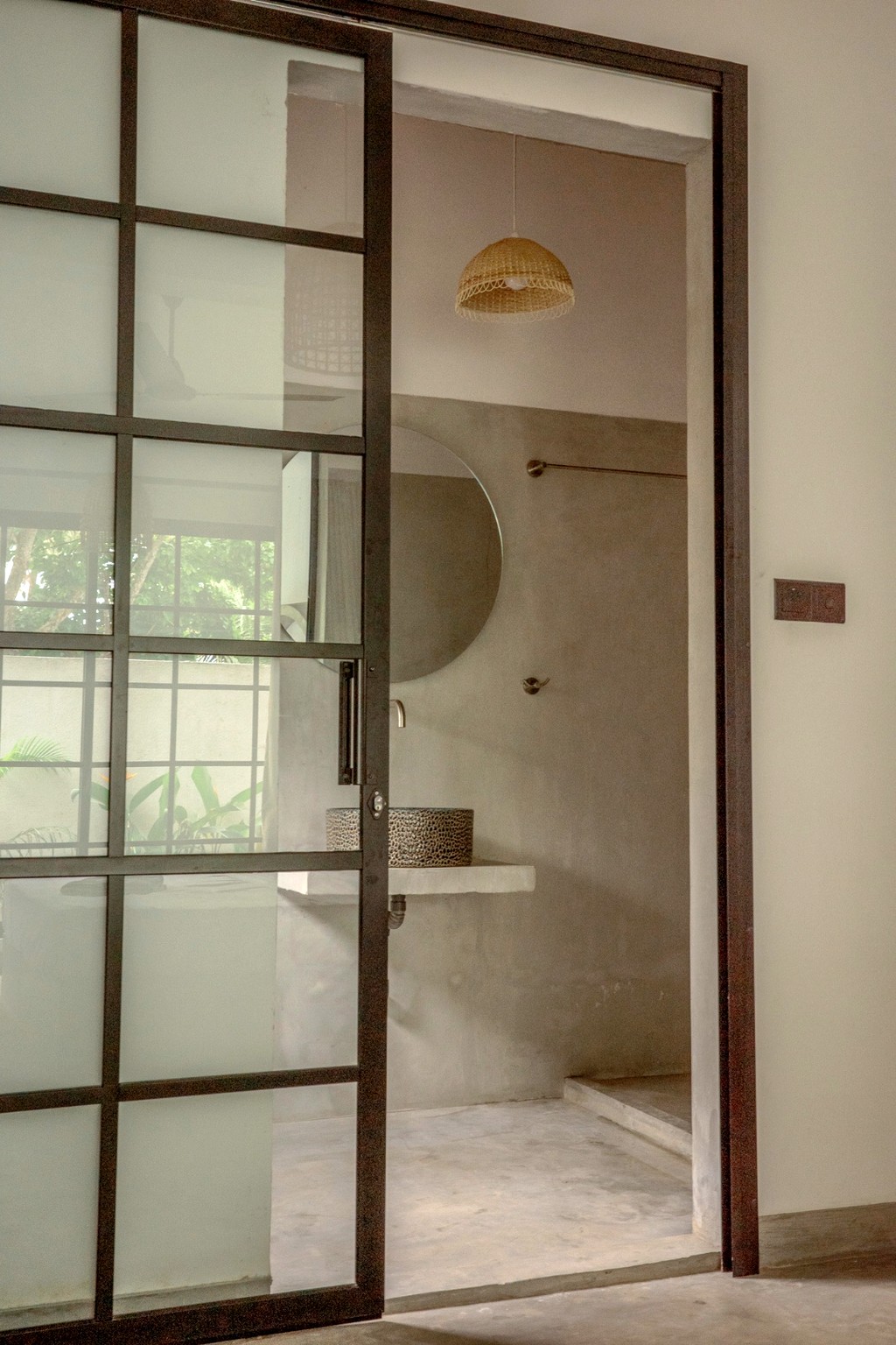 Casa bathroom through the glass grid door · vessel sink and round mirror