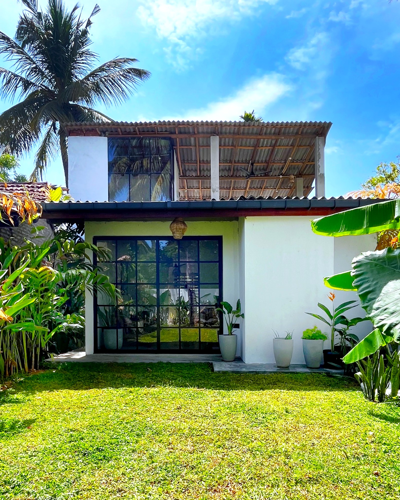 Casa, white facade with gridded glazing and the open upper terrace