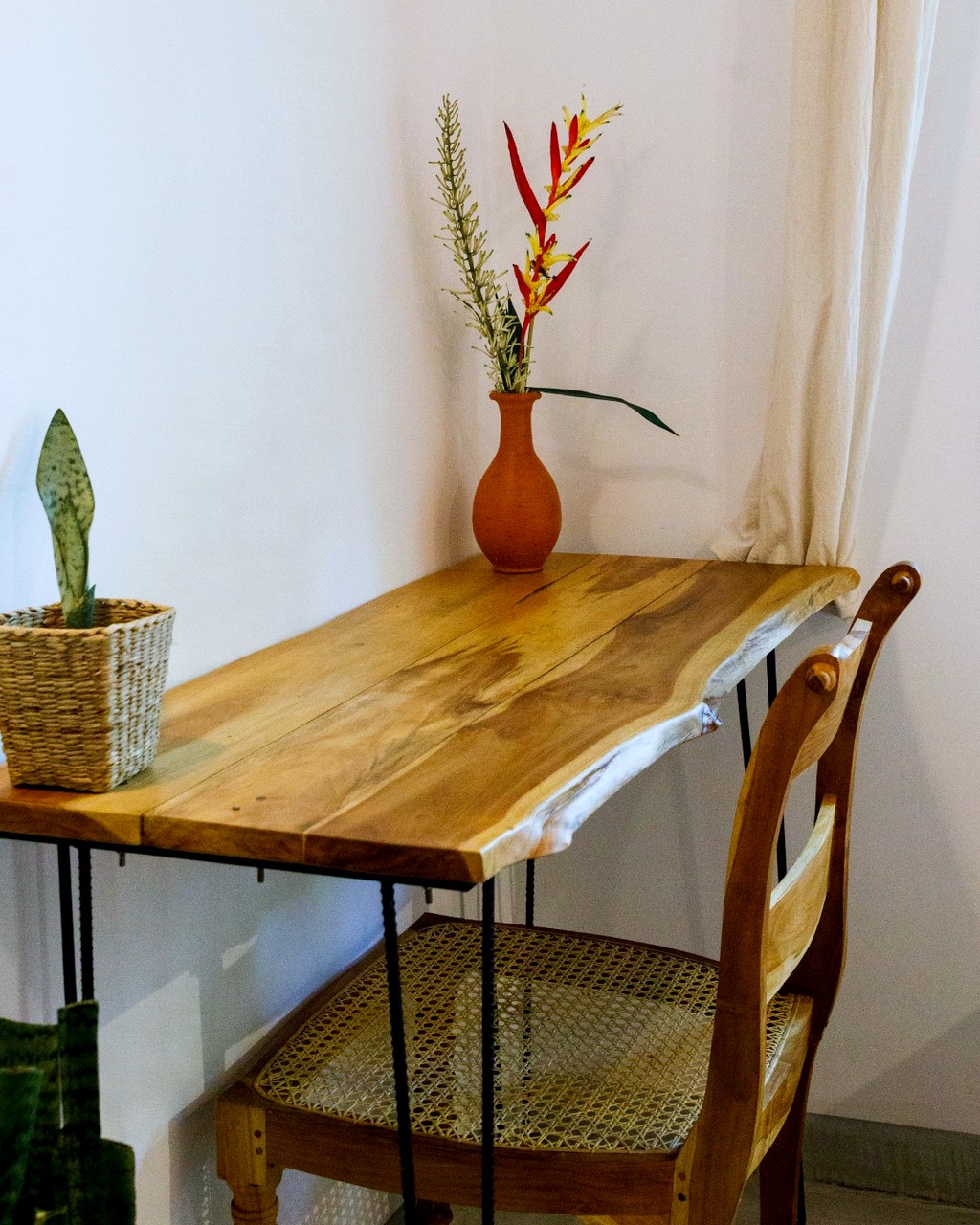 Safiya bedroom two · live-edge desk, cane chair, red flowers